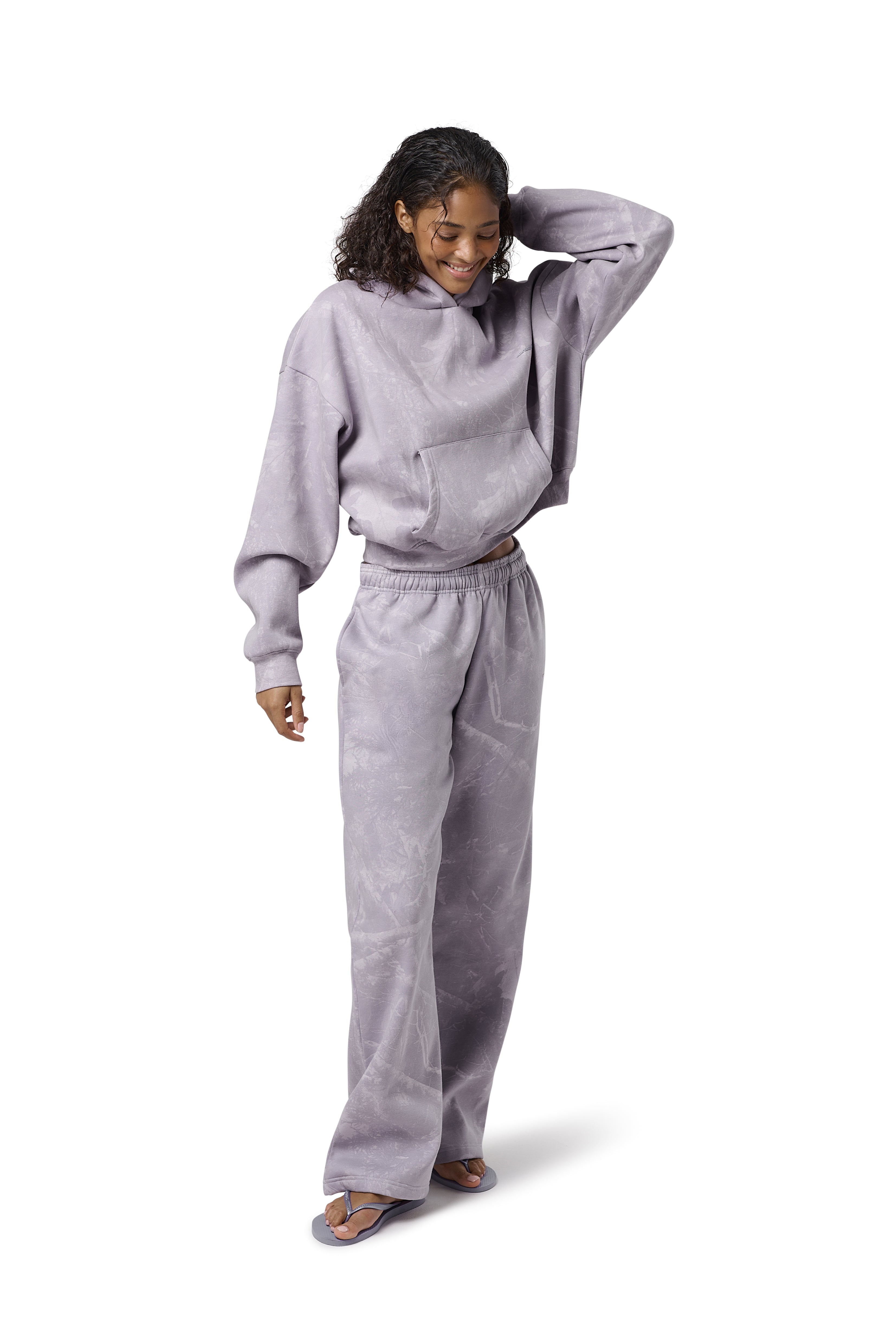 Lilac high-waisted straight-leg sweatpants with subtle twig camo print, elasticated drawstring waist, and embroidered Sisters & Seekers logo. Soft cotton-blend fabric in sizes 2XS–3X, available in Petite, Regular, and Tall lengths